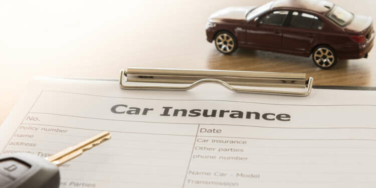 car insurance application form with car model and key remote on desk.